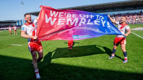 Hull KR's Joe Burgess and Mikey Lewis stood on the pitch holding aloft a flag saying "We're off to Wembley"