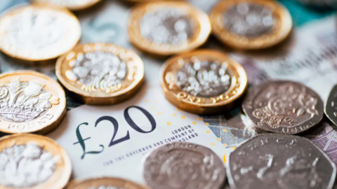 An aerial photograph of a £20 note, surrounded by coins
