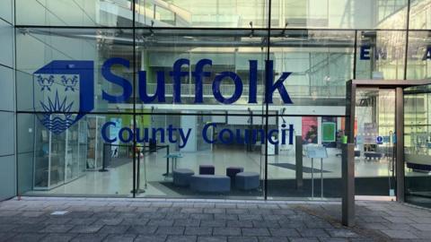 A glass fronted building with big blue letters which say Suffolk County Council 