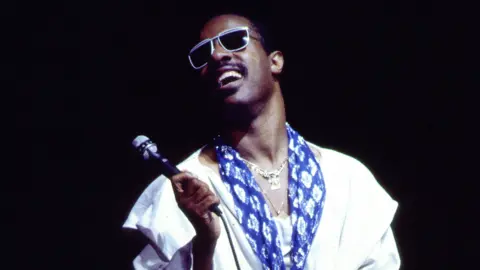 Stevie Wonder holds a microphone as he sings in an archival image