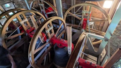 A set of church bells connected to large wheels in a church tower