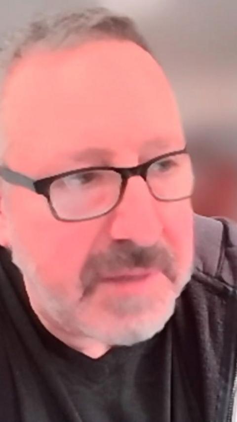 Man wearing black glasses being interviewed over video call