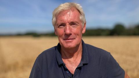 Farmer Richard Langton in a blue shirt standing in the sunshine