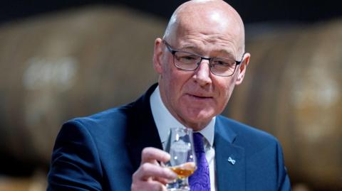 john swinney with a glass of whisky