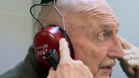 Swindon Town Manager Ian Holloway wearing headphones