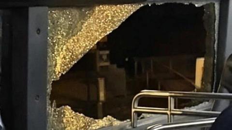 A smashed window on the top-deck of a bus