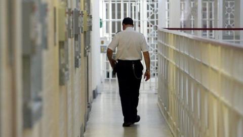 Prison officer walking down corridor in a prison