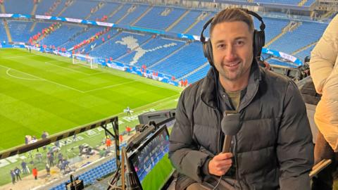 Mike Minay holds a mic at football stadium