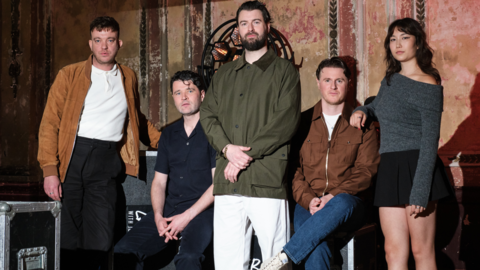 The five members of Courteeners standing in a dilapidated room with tour equipment visible