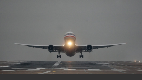 A plane comes into land at an empty runway at Manchester Airport with its landing land on underneath its cockpit