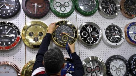 A man changes clocks in a store