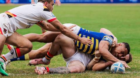 Albert Hopoate touches the ball down under pressure from Bulls defenders