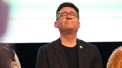 Andy Burnham with his eyes closed and head looking up to the sky