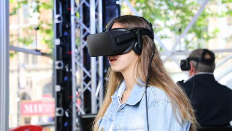 Woman with brown hair wearing a black VR headset