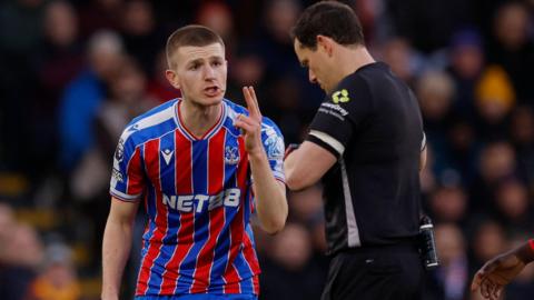 Adam Wharton holds his hand up to referee Darren England