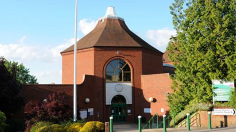 Mole Valley District Council's hexagonal building made of red brick with an arched window on one side