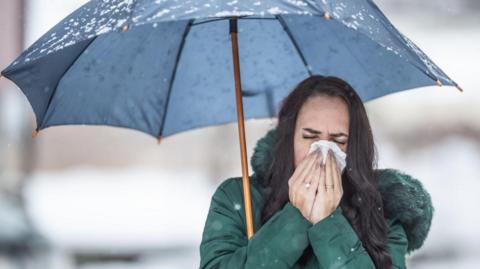 Woman with umbrella sneezing