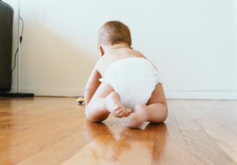 A baby crawling on a wooden floor