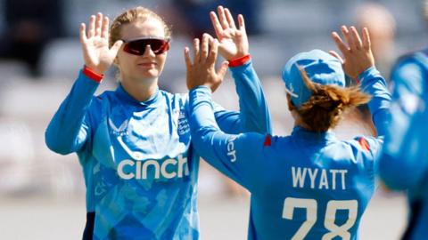 Charlie Dean (left) and Danni Wyatt (right) celebrate a wicket for England