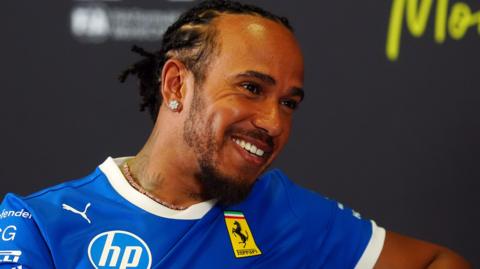 Lewis Hamilton smiling while wearing a blue Ferrari t-shirt during the Thursday news conference before the Italian Grand Prix