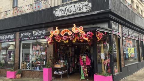 Cliftonville Junktion vintage shop on Northdown Road with pink planters outside the entrance and a sign in the window that reads 'Peace On Earth'