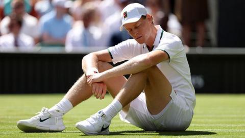 Jannik Sinner sits on the grass