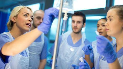 Nursing students watching as a drip is administered