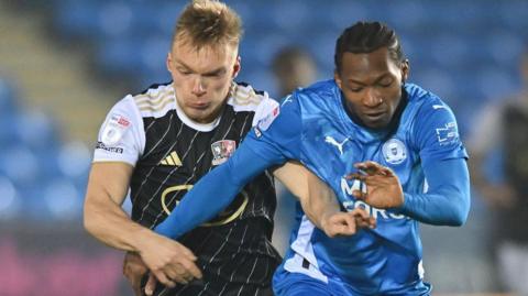 Tayo Edun of Peterborough United tries to hold off Exeter City's Ilmari Niskanen