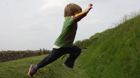 A young boy jumping on grass