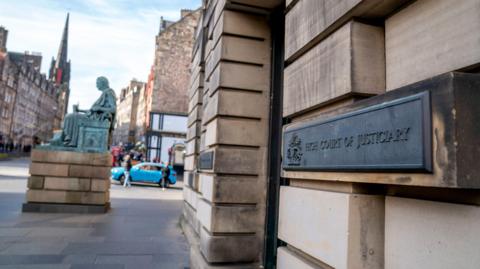 A general view of the outside of the high court in Edinburgh. It is a sandstone building with a brass sign