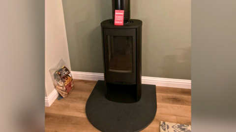 A black wood burning stove inside a property with a green wall and wooden floors.