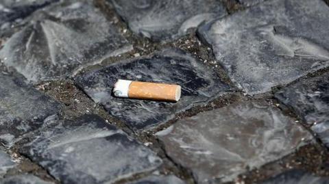 File image showing a burnt cigarette butt on a grey cobbled street