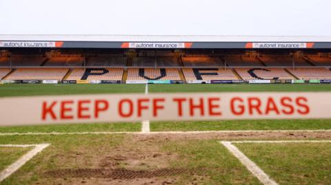 A general view inside Vale Park of mud on the pitch and a 'keep off the grass' sign