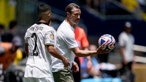 Niko Kovac hands the ball to a player
