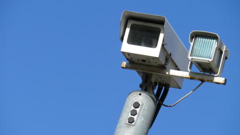 A CCTV camera against a bright blue sky.