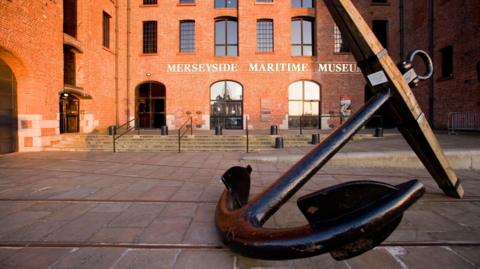 Large anchor in front of entrance to redbrick warehouse accommodating Merseyside Maritime Museum