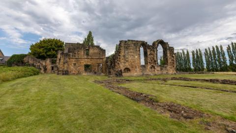 The ruins of a medieval abbey on a grassed area