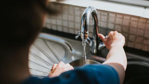 Person turning kitchen tap on