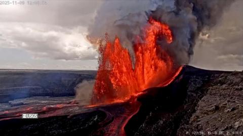 Red lava and smoke shoots from black mountains into the air
