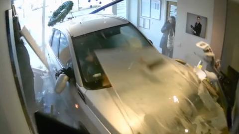 Silver car crashes through shop window.