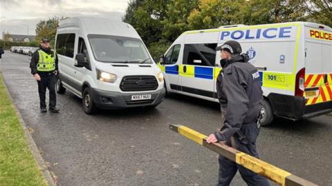 Two police vans and officers standing in the road.
