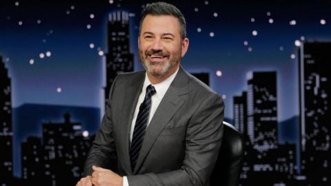 Jimmy Kimmel sits at a desk hosting his late night show