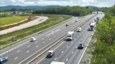 A screenshot from a motorway traffic camera showing traffic moving freely along the northbound carriageway. 