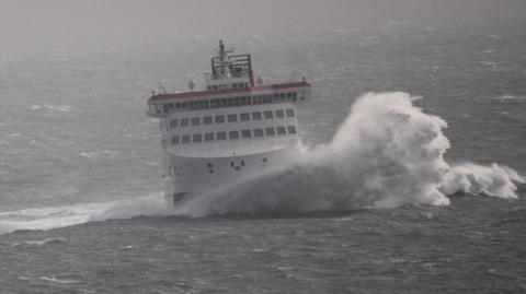 The Manxman - a large white ferry - in rough seas with a wave breaking against the bow.
