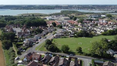 An aerial view of the village of Brantham. In the distance is an estuary.