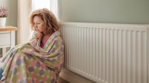 A woman in a blanket next to a radiator