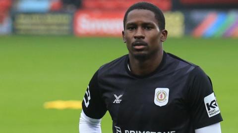 Crewe striker Shilow Tracey in his training kit, going through some warm-up stretches before a game