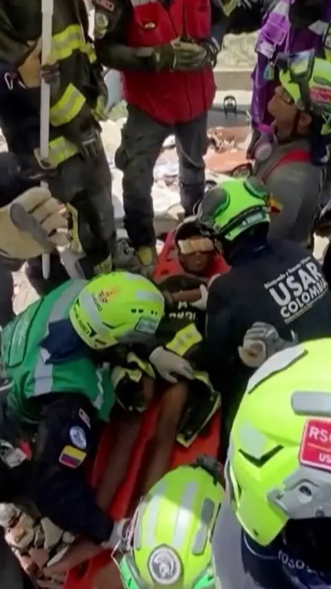 A boy on a stretcher with rescue workers around him