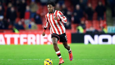 Andre Brooks in a red and white striped Sheffield United shirt running with the ball during a game.
