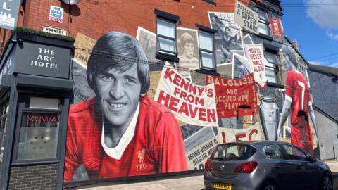 A large colourful mural features Sir Kenny Dalgleish and a selection of newspaper cuttings and photos.